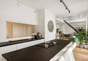 una cucina con piano di lavoro nero e armadietti bianchi di Sky loft - Luxurious Penthouse - Antwerp 180 m² ad Anversa