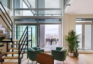 a living room with green chairs and a staircase at Sky loft - Luxurious Penthouse - Antwerp 180 m² in Antwerp
