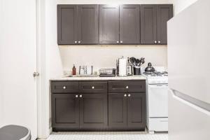uma cozinha com armários pretos e electrodomésticos brancos em Apartment 227: Upper West Side em Nova York