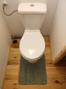 a white toilet in a bathroom with wooden floors at chalet de Campagne avec option SPA - petit déj 