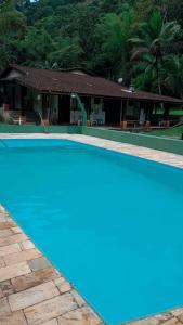 una piscina azul frente a una casa en Hostel Recanto Caiçara, en São Sebastião