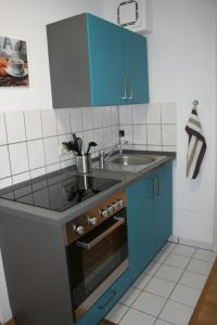 a kitchen with blue cabinets and a sink at Apartment Messezimmer Flughafen Köln Bonn in Rösrath