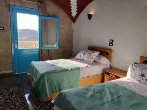a bedroom with two beds and a blue door at Nubian Hights guesthouse in Shellal