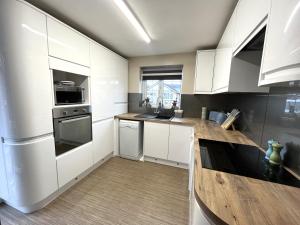 a kitchen with white cabinets and a wooden counter top at Tranquil 3-bedroom bungalow 