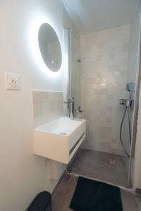 Un baño blanco con lavabo y espejo. en Le petit bellifontain, en Fontainebleau