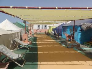 eine überdachte Terrasse mit Stühlen, Tischen und Zelten in der Unterkunft Auberge Triskell in Nouakchott