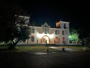 ein großes weißes Gebäude mit einem Eingang in der Nacht in der Unterkunft Cortijo la amazona in Sevilla