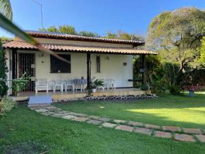 a small white house with chairs and a yard at Casinha aconchegante perto da praia Guarajuba - Ba in Guarajuba