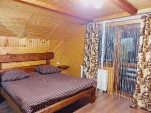 ein Schlafzimmer mit einem Bett in einem Zimmer mit einem Fenster in der Unterkunft Villa Zgarda1 in Mykulytschyn