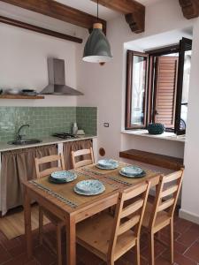 una cucina con tavolo in legno, sedie e lavandino di ficodindia Suite & Apartments a Santo Stefano di Camastra