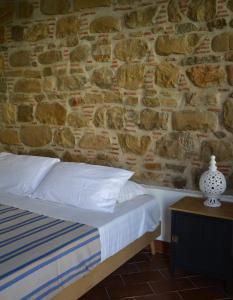 Bett in einem Zimmer mit einer Steinmauer in der Unterkunft ficodindia Suite & Apartments in Santo Stefano di Camastra