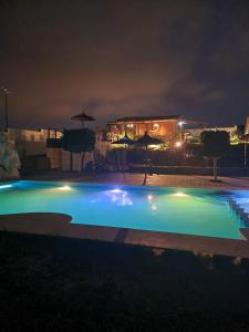 una gran piscina por la noche con luces en LA GRANJA en Tetuán