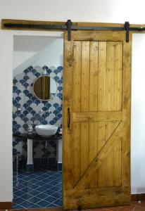 ficodindia Suite & Apartments في سانتو ستيفانو دي كاماسترا: باب خشبي في حمام مع حوض