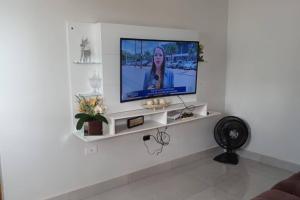 uma sala de estar com televisão numa parede branca em Chácara Horiental em Maringá