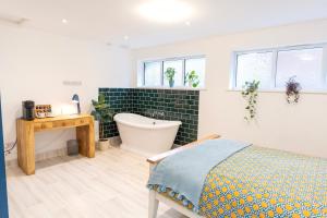 a bathroom with a tub and a bed and a bath tub at Soho House in Bordon in Bordon