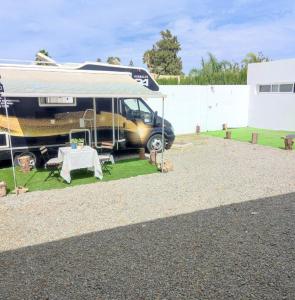 a camper van parked in a yard with a table at Paraíso del bienestar in Cádiz