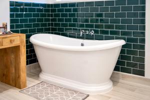 a bath tub in a bathroom with green tiles at Soho House in Bordon in Bordon