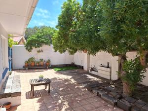 um pátio com uma mesa e uma árvore em Sea View em Yzerfontein