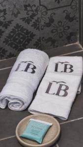twee handdoeken met de H erop op een badkamerbar bij Lali Beach Hotel Boutique in Sonsonate