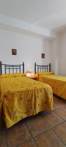 two beds with yellow sheets in a room at Casa Rural Sara in Pinos del Valle