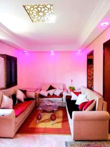 una sala de estar con iluminación rosa y sofás en Joli Appartement Vue Montagne en Xauen