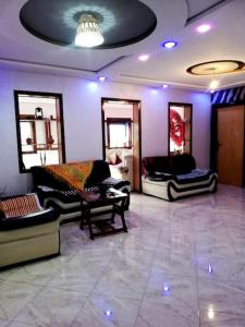 una sala de estar con sofás, sillas y luces púrpuras en Joli Appartement Vue Montagne en Xauen