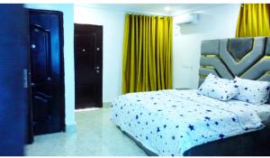 ein Schlafzimmer mit einem Bett und gelben Vorhängen in der Unterkunft Logan Point Apartment in Benin-Stadt