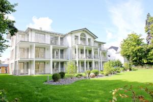 una vista exterior de una gran casa blanca con patio en moderne Ferienwohnung mit eigener Sauna und Balkon - Villa Pauline FeWo 06, en Göhren