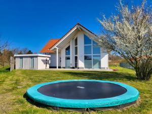 a house with a large trampoline in the yard at modernes Ferienhaus mit Kamin, Garten und eigener Sauna - Ferienhaus Meerfreude in Vaschvitz