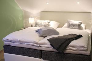 a large bed with white sheets and pillows on it at modernes Ferienhaus mit Kamin, Garten und eigener Sauna - Ferienhaus Meerfreude in Vaschvitz