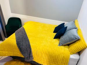 Un dormitorio con una cama amarilla con almohadas. en Comfort, en Kathu