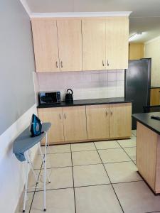 a kitchen with wooden cabinets and a black refrigerator at Comfort in Kathu