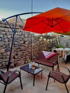 un patio con una mesa y una sombrilla roja en Casa Mamá Vicky - Valle del Colca, en Coporaque