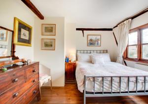 a bedroom with a bed and a dresser and windows at Old Post Office Cottage in Poringland