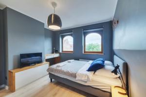 een blauwe slaapkamer met een bed en een televisie bij Dream Loft Motlava River in Gdańsk
