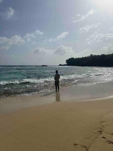 een man op het strand die naar de oceaan kijkt bij Villa Maat 5 minutes to Winnifred Beach in Port Antonio