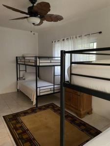um quarto com 3 beliches e uma ventoinha de tecto em Villa Maat 5 minutes to Winnifred Beach em Port Antonio