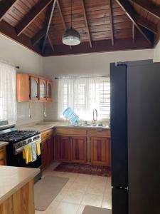 cocina con armarios de madera y nevera negra en Villa Maat 5 minutes to Winnifred Beach, en Port Antonio