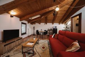 Una sala de estar con un sofá rojo y un televisor. en Maison Petit Rouge by Hili, en Aosta