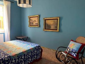 a bedroom with blue walls with a bed and a chair at Casa Mariuccia in Anzio
