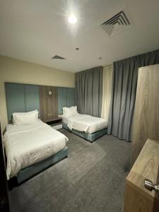 a hotel room with two beds and curtains at Rawabi Alkhobar Suites in Al Khobar