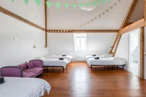 Maison de vacances & weekend lumineuse, spacieuse et au calme,- 18 personnes في Bailleul-la-Vallée: غرفة بها أربعة أسرة وكراسي أرجوانية