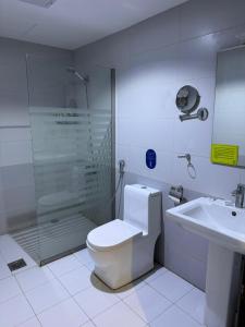 a bathroom with a shower and a toilet and a sink at Rawabi Alkhobar Suites in Al Khobar
