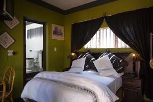 a bedroom with a bed with green walls and a window at Nthateng Bed and Breakfast in Soweto