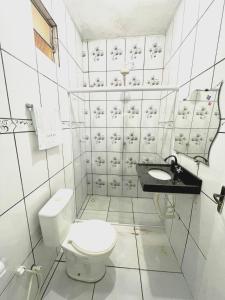 a white bathroom with a toilet and a sink at Casa de serra -3 quartos in Ubajara