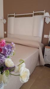 a white vase with flowers sitting on a bed at Hotel Gargallo in Syracuse