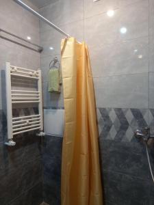 a shower with a yellow shower curtain in a bathroom at Malacia apartments in Yerevan