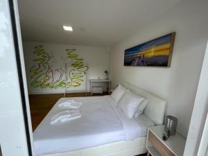 ein Schlafzimmer mit einem weißen Bett und einem Gemälde an der Wand in der Unterkunft Large double room 2 with en-suite bathroom and Belcony in Oeiras