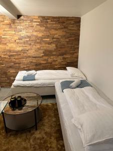 two beds in a room with a table and a brick wall at A Place To Stay Stavanger, apartment 1 in Stavanger