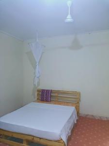 un piccolo letto in una stanza con parete bianca di Jamagere Homes near Palm Oasis a Garissa